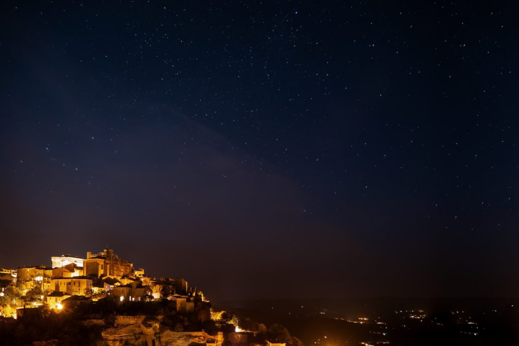 Une ville est au sommet d'une colline la nuit.