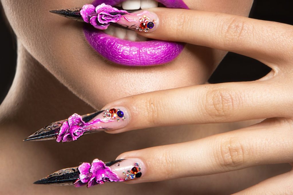 Une femme avec des ongles violets et des fleurs sur les lèvres.