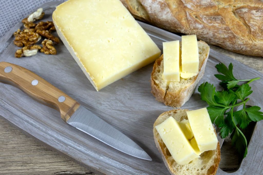 Fromage et pain sur une planche à découper en bois avec persil et noix.