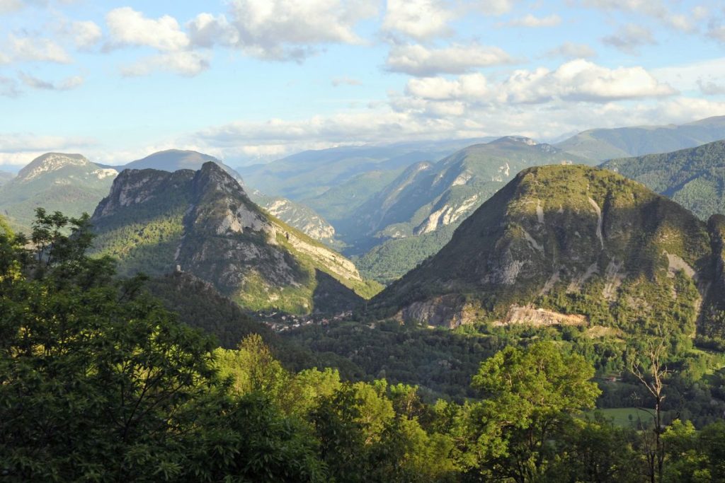 Une vue sur une vallée avec des arbres et des montagnes en arrière-plan.