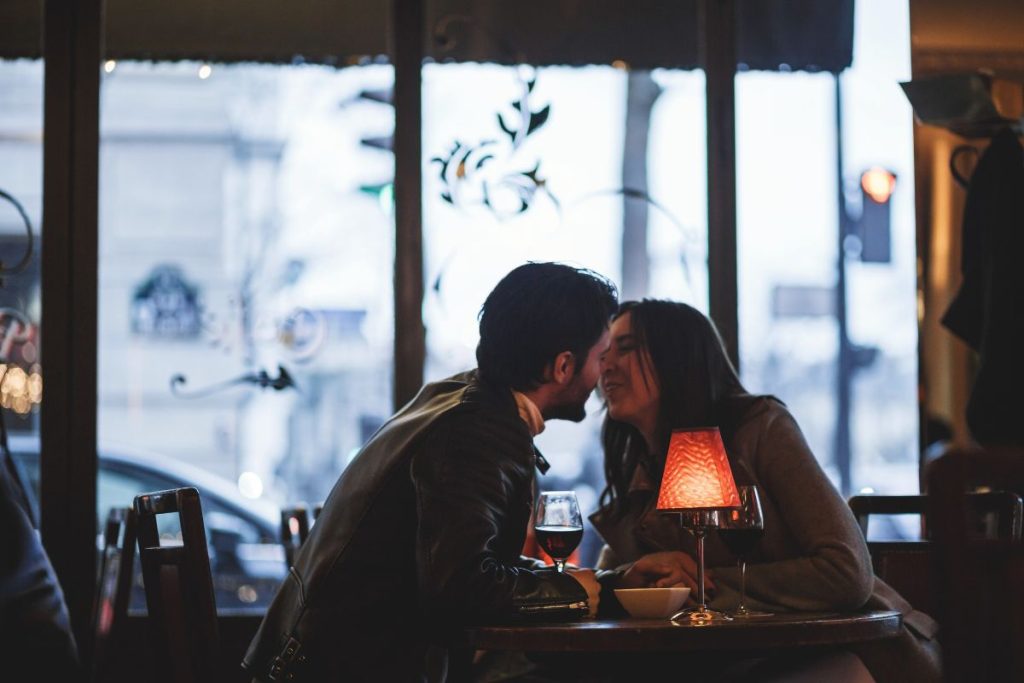 Un couple s'embrassant à une table dans un restaurant.