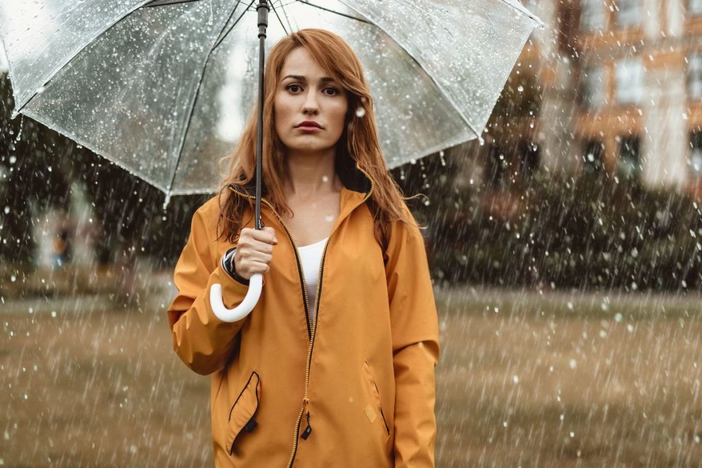 Une femme tenant un parapluie sous la pluie.