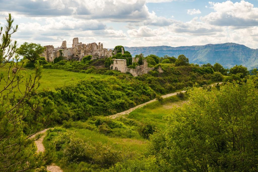 Un château se dresse au sommet d’une colline surplombant une vallée.