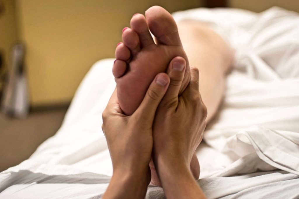 Une personne qui reçoit un massage des pieds dans un lit d'hôpital.