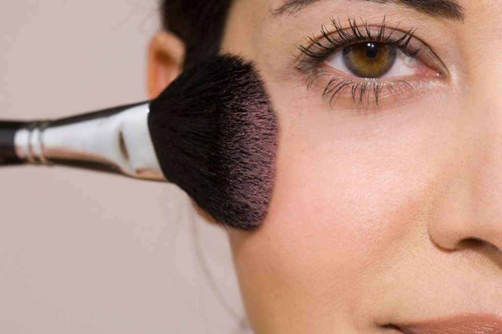 Une femme utilise un pinceau pour se maquiller les yeux.