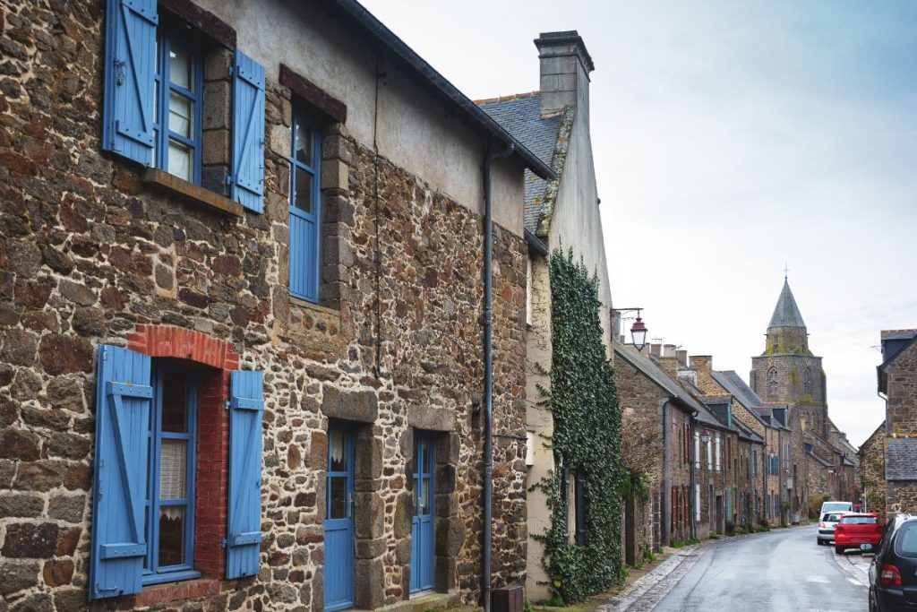 Une rue bordée d'immeubles en pierre et de volets bleus.