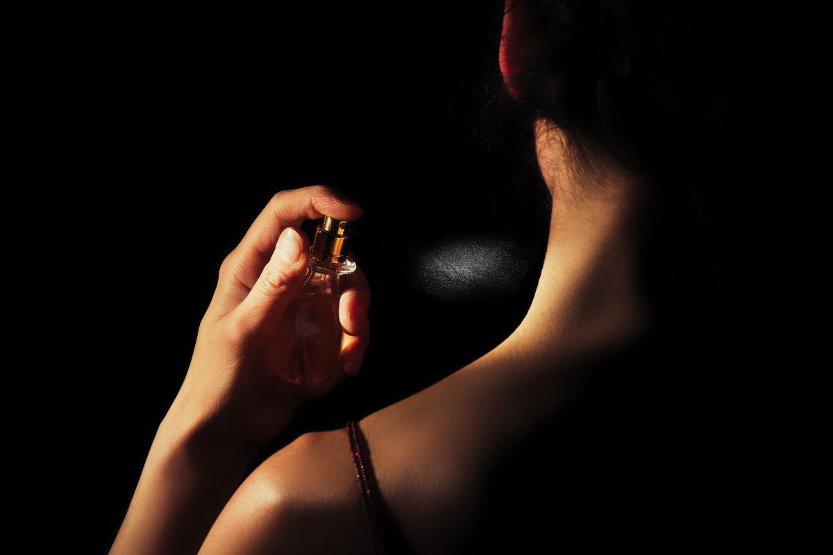 Une femme tient un flacon de parfum à la main.