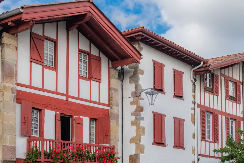 Une maison avec des volets rouges et un balcon.