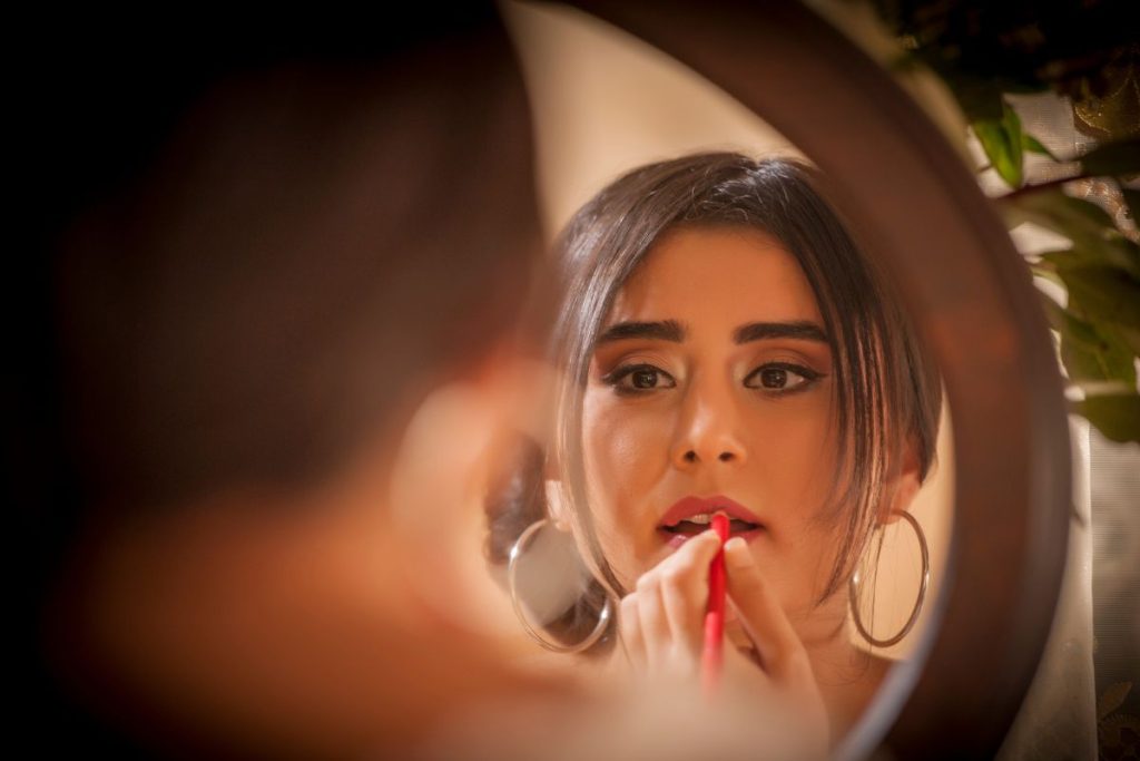 Une femme se brosse les dents devant un miroir.