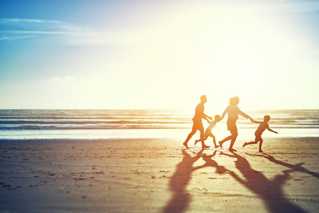 Une famille court sur la plage au coucher du soleil.