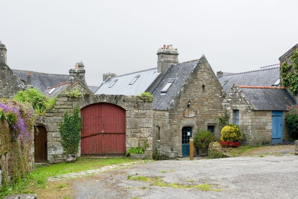 Une vieille maison en pierre avec une porte rouge.