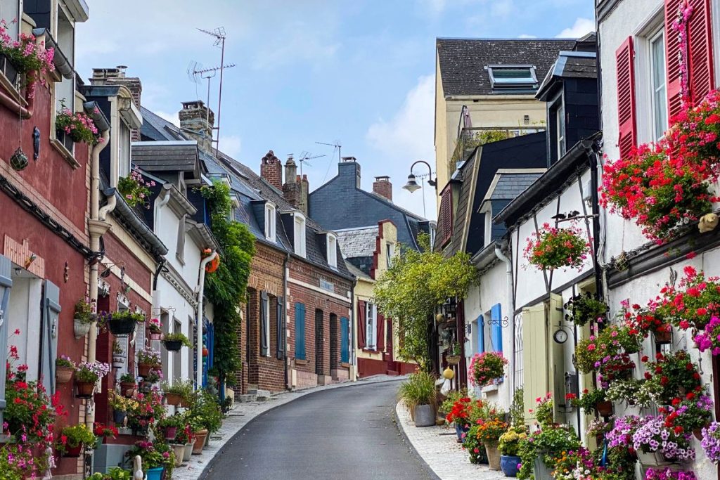 Une rue étroite bordée de maisons colorées et de fleurs.