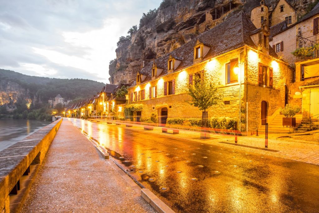 Une rue mouillée dans une ville près d’une falaise au crépuscule.