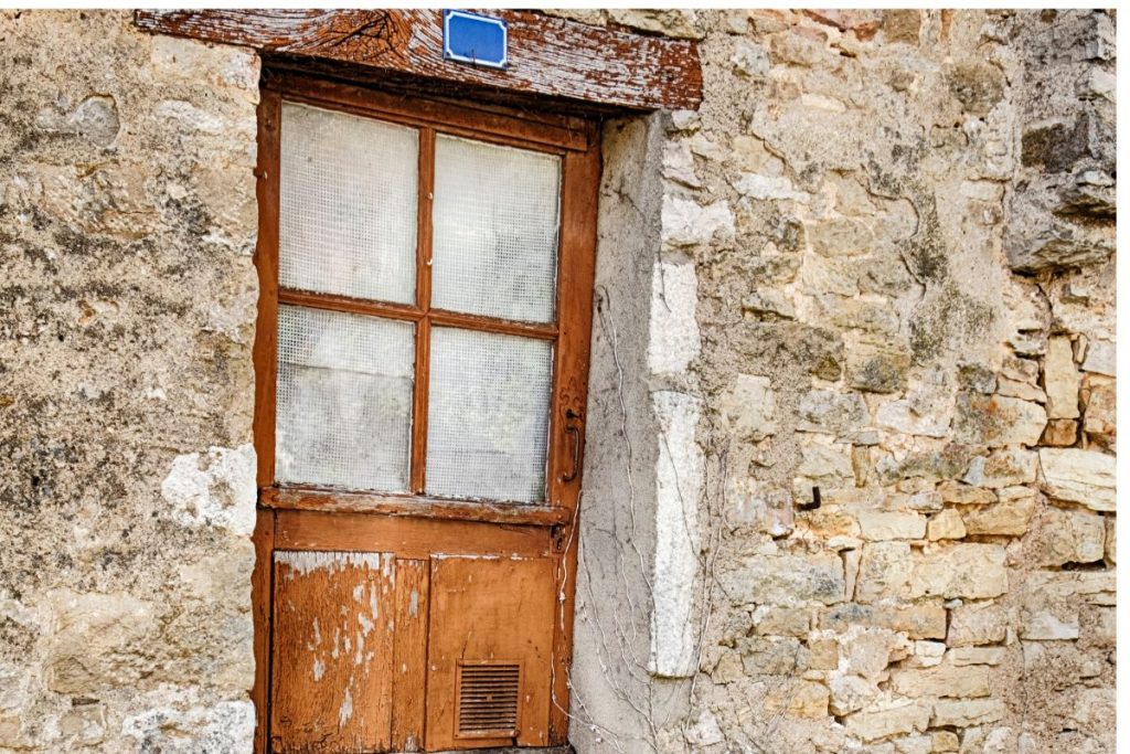 Une vieille porte en bois dans un bâtiment en pierre.