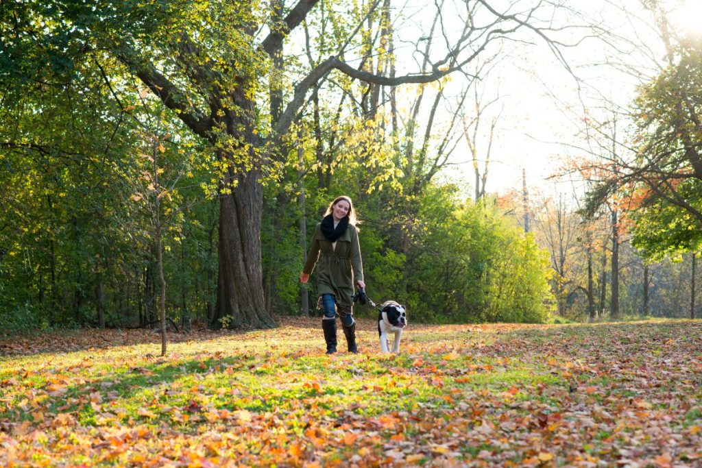 Une femme promenant son chien dans un parc en automne.