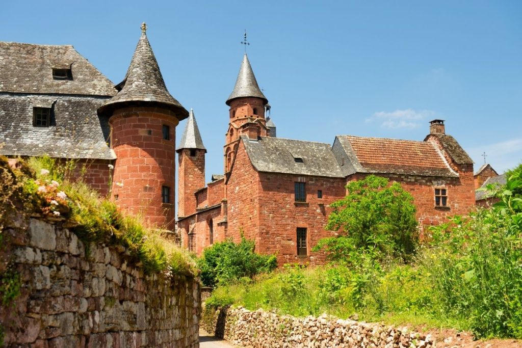 Un château en brique rouge avec des tourelles en arrière-plan.