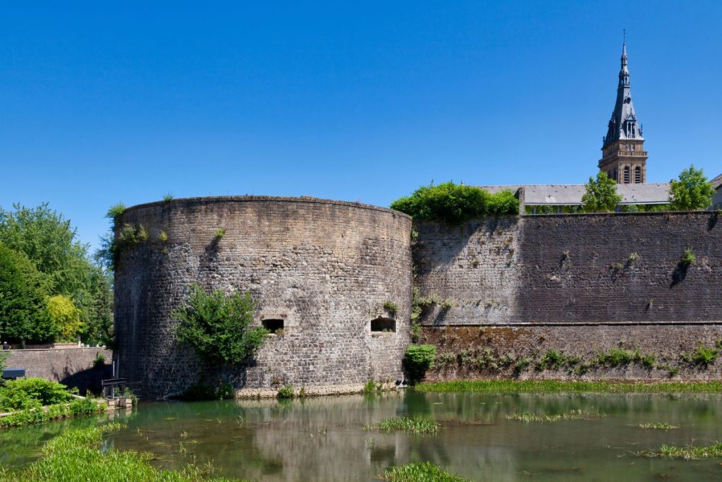Les murs d’un château avec un étang en arrière-plan.