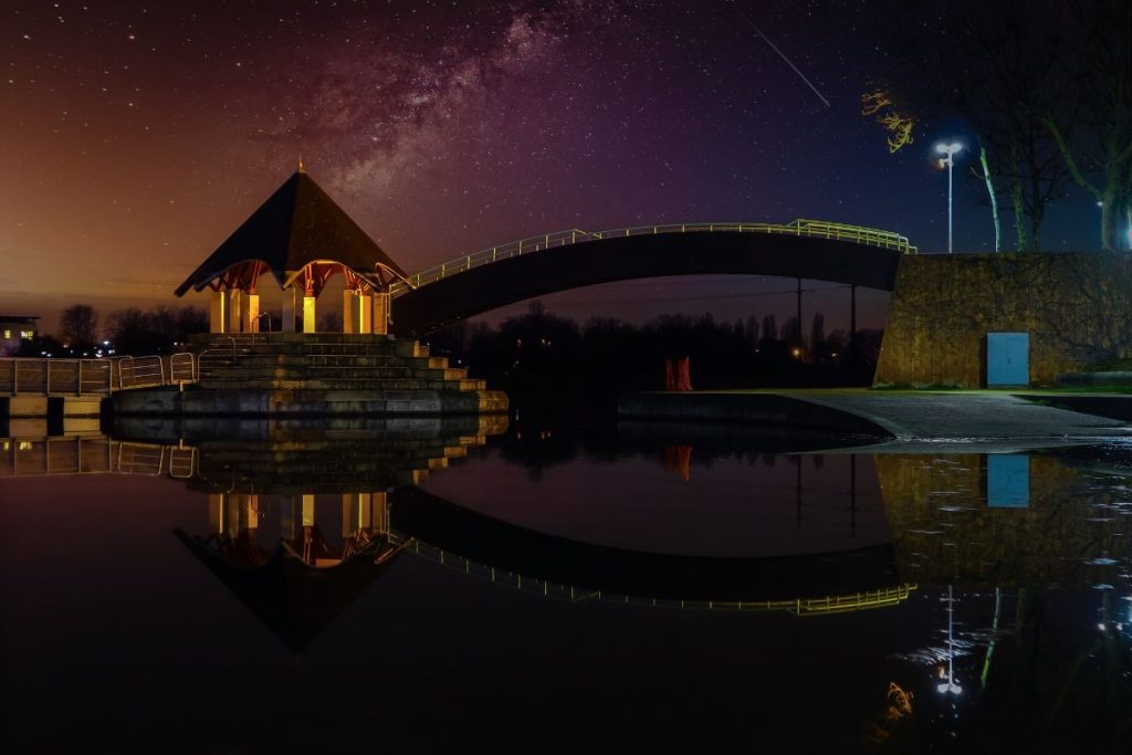 Un pont se reflète dans un lac la nuit.