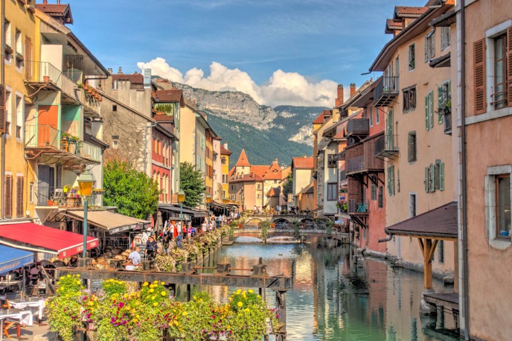 Un canal au milieu d’une ville avec des montagnes en arrière-plan.