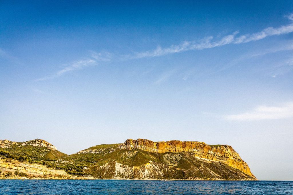 Un bateau est dans l’eau près d’une falaise rocheuse.
