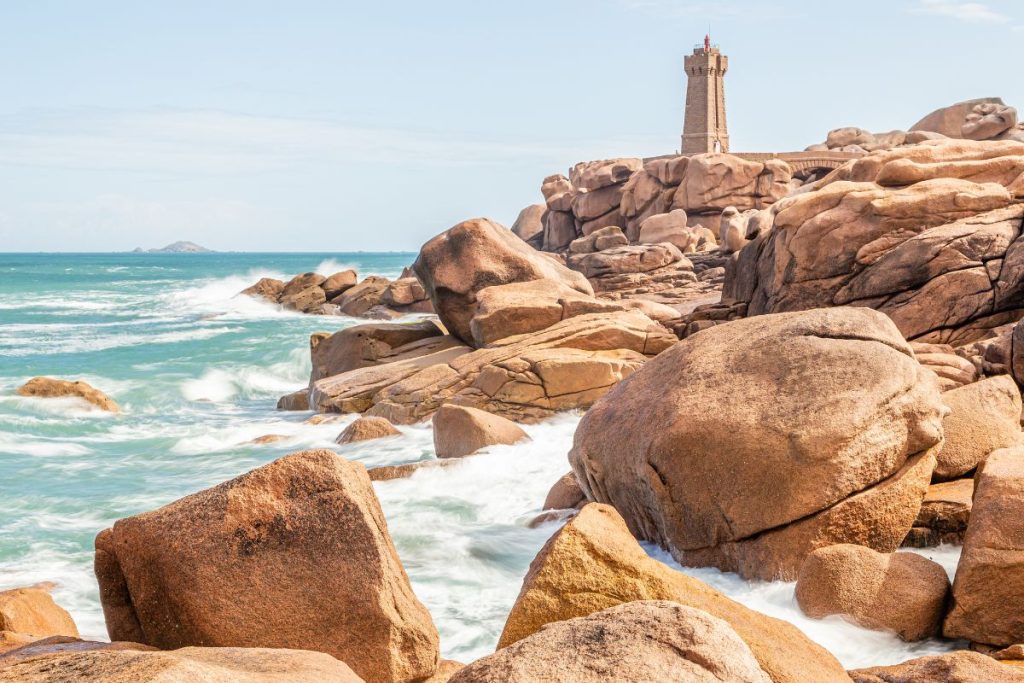 Un phare se trouve au sommet des rochers près de l’océan.