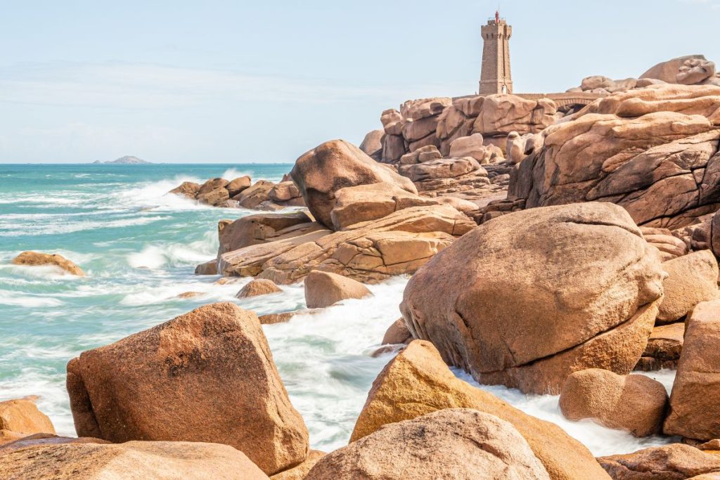 Un phare se trouve au sommet des rochers près de l’océan.