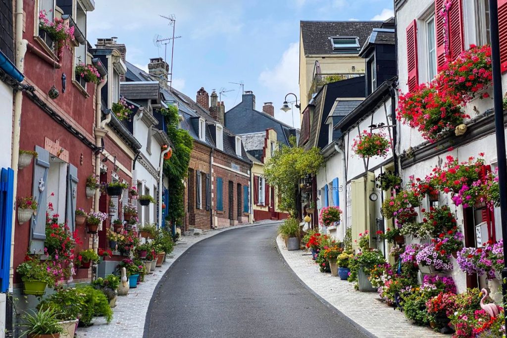 Une rue étroite bordée de maisons colorées et de fleurs.