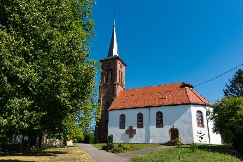 Une église avec un clocher au milieu d'un champ.