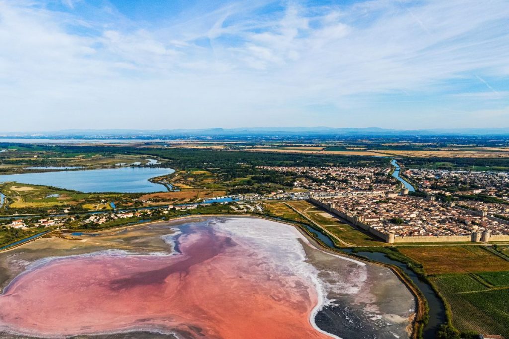 Une vue aérienne d'un lac salé rose et d'une ville.