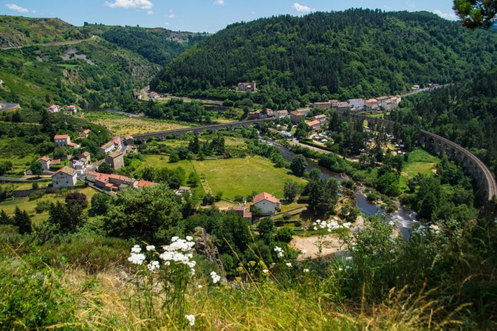 Une vue d'un village dans une vallée arborée et fleurie.