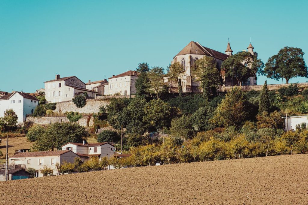 Une église au sommet d’une colline avec un champ en arrière-plan.