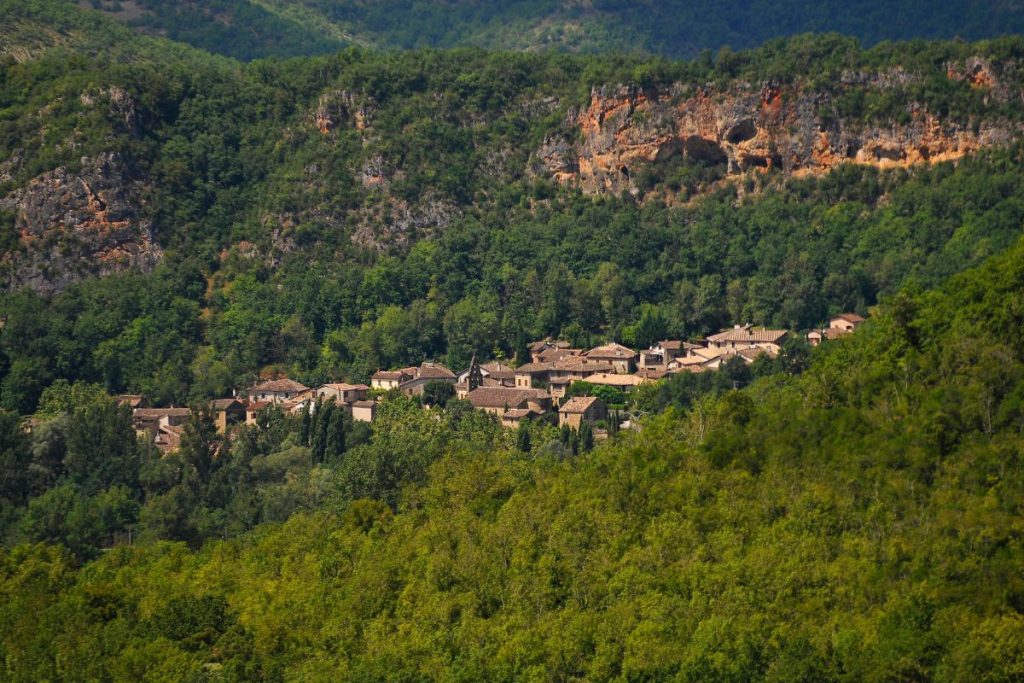 Un village se trouve au sommet d’une montagne entouré d’arbres.