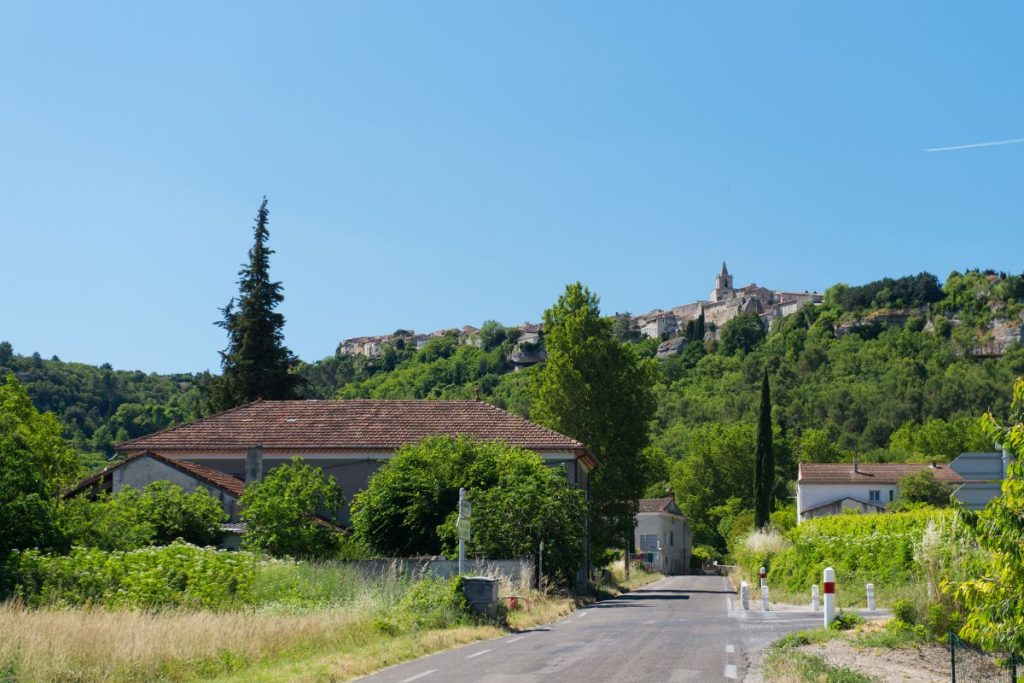 Une route menant à un village avec une colline en arrière-plan.