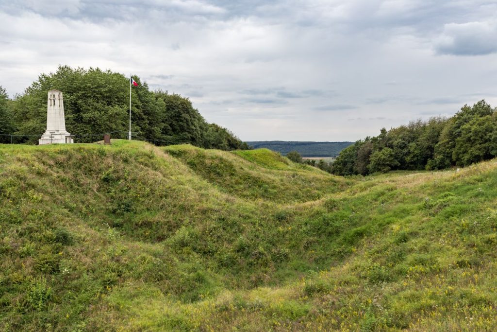 Une colline herbeuse avec un monument au milieu.