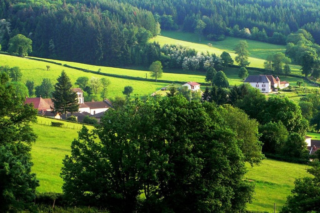 Paysage rural avec une verdure luxuriante et des maisons dispersées.