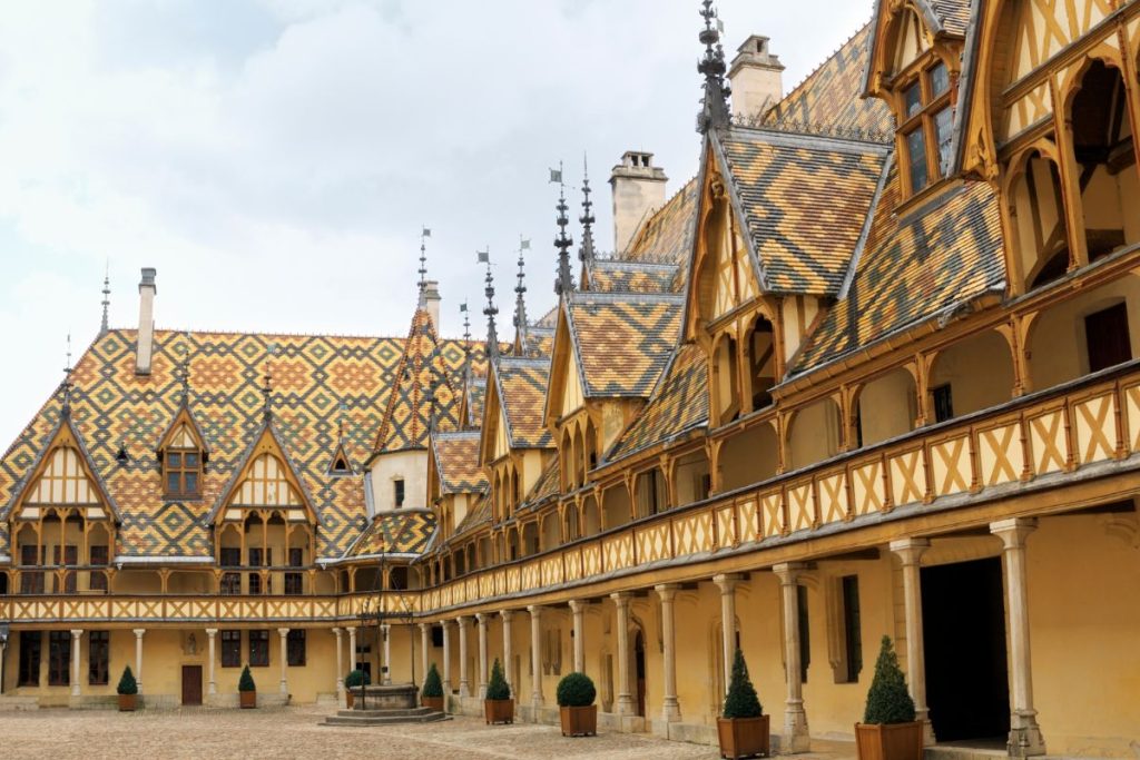 Château français traditionnel avec toit de tuiles multicolores et galerie ouverte voûtée.