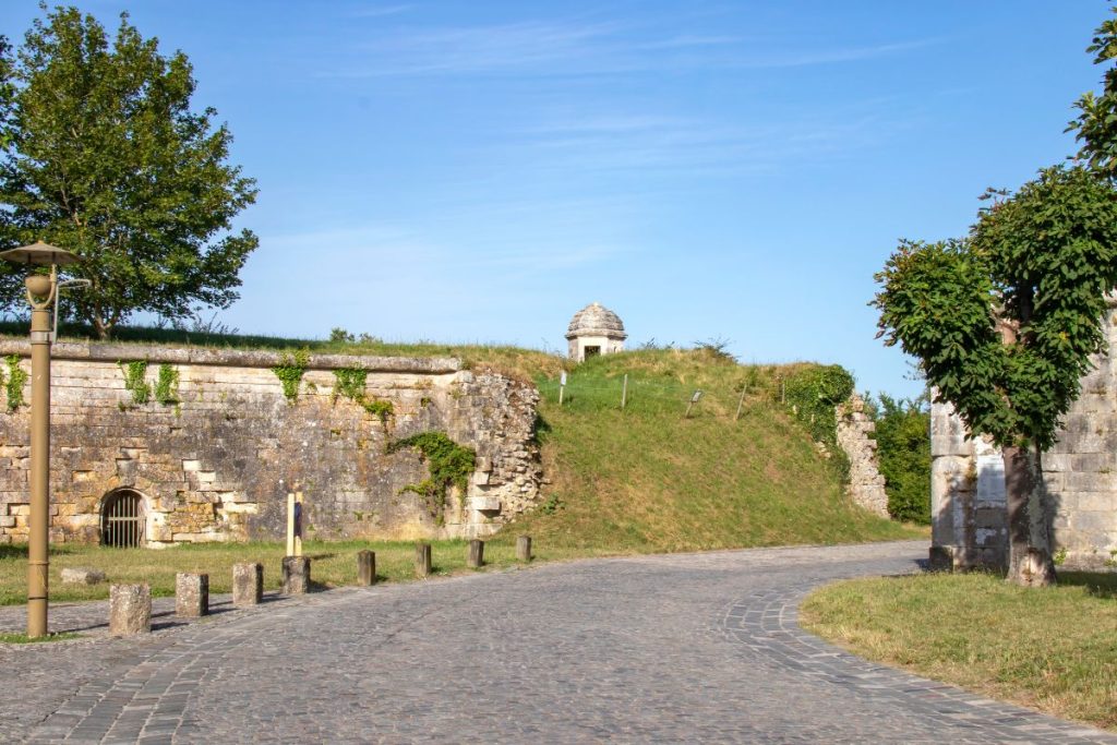 Fortifications historiques en pierre à côté d'un chemin pavé par une journée ensoleillée.