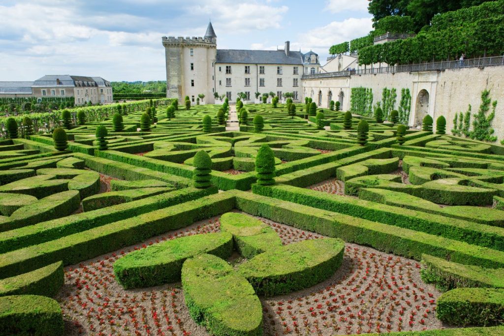 Jardin à la française avec labyrinthe de haies géométriques devant un château classique.