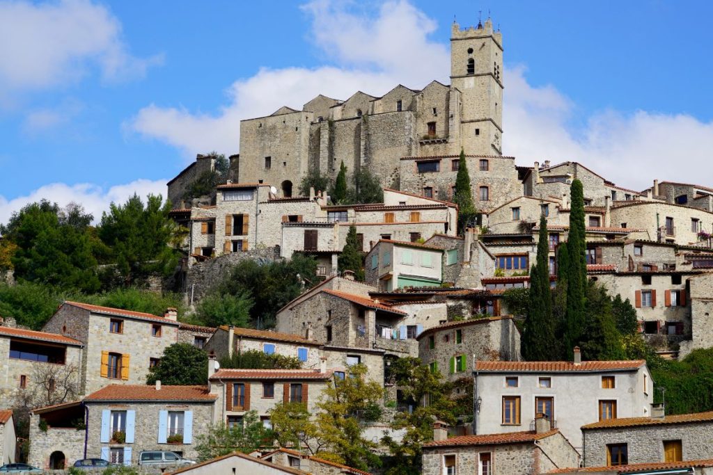 Village médiéval perché avec bâtiments en pierre et château fort.