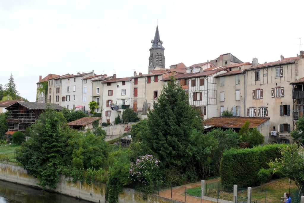 Une vue sur la rivière d'une vieille ville européenne avec des bâtiments historiques et un clocher d'église.