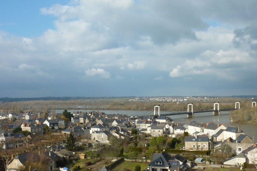 Une vue panoramique d'une ville avec un pont enjambant une rivière, sous un ciel nuageux.