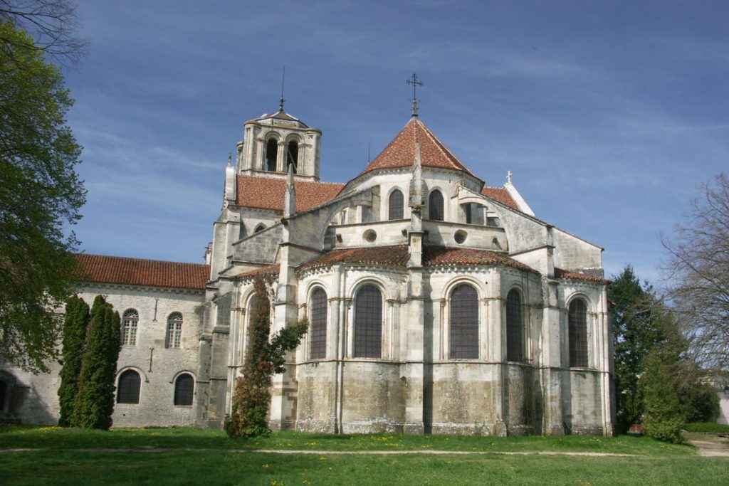 Église historique en pierre avec deux clochers sous un ciel clair.