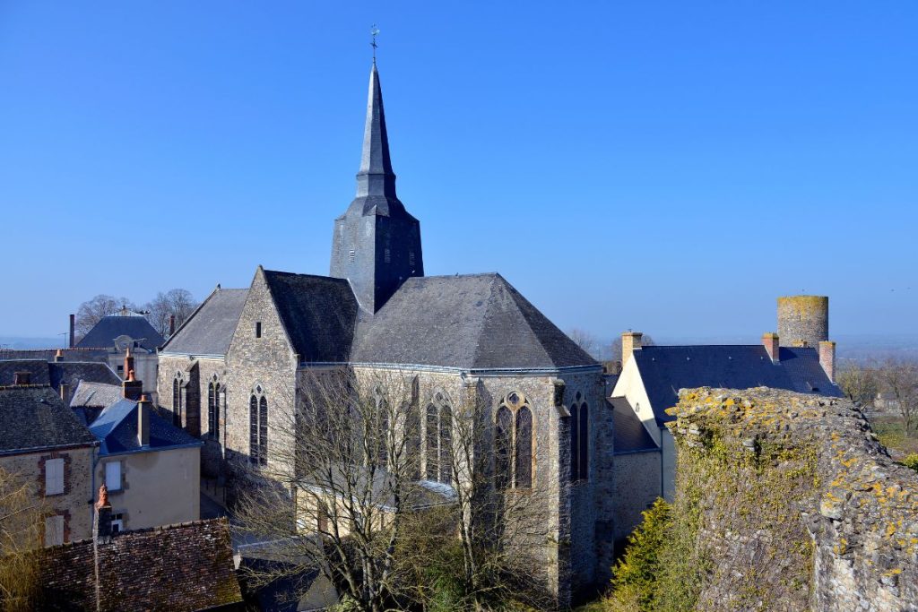 Église historique en pierre avec flèche dans un village européen.