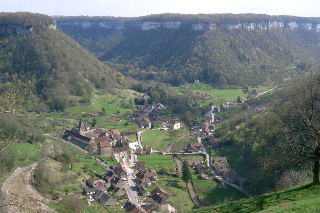 Une vue panoramique sur un petit village niché dans une vallée luxuriante entourée de collines boisées.