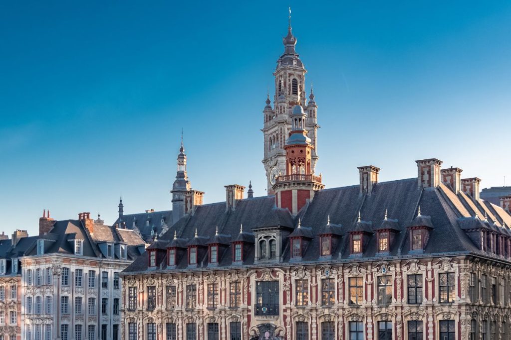 Architecture européenne historique avec des façades ornées et un clocher proéminent sur un ciel bleu clair.