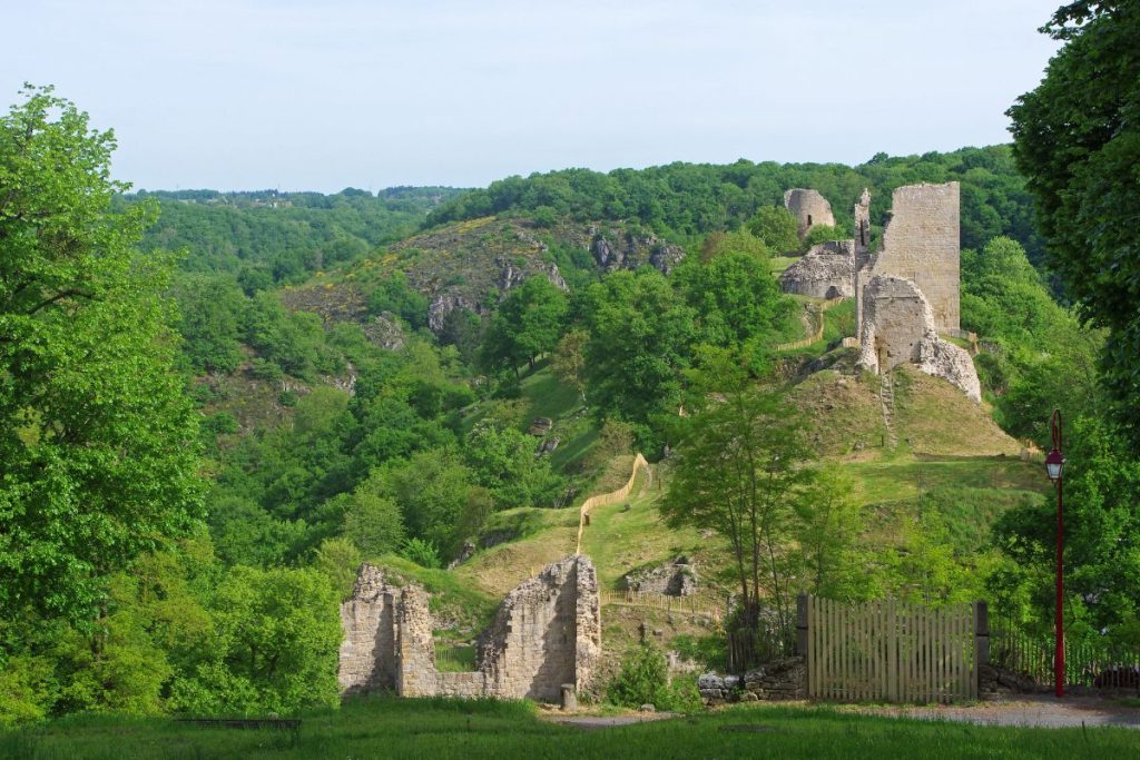 Ruines d'une ancienne forteresse au milieu de collines verdoyantes et d'arbres.