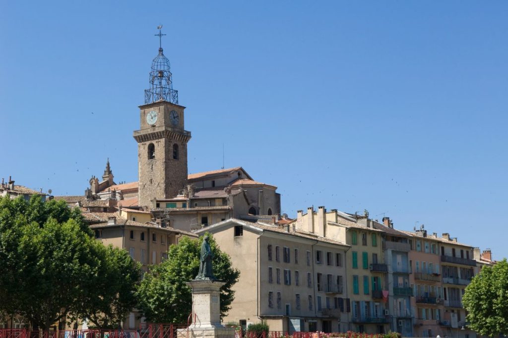 Une vue sur une ville européenne pittoresque avec des bâtiments colorés et une haute tour de l'horloge sous un ciel bleu clair.