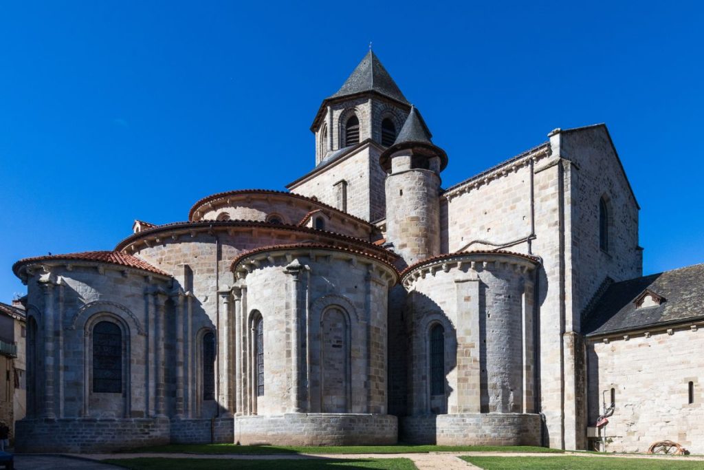 Église en pierre de style roman avec un haut clocher central, plusieurs absides semi-circulaires et un fond de ciel bleu clair. Église en pierre de style roman avec un haut clocher central, plusieurs absides semi-circulaires et un fond de ciel bleu clair.