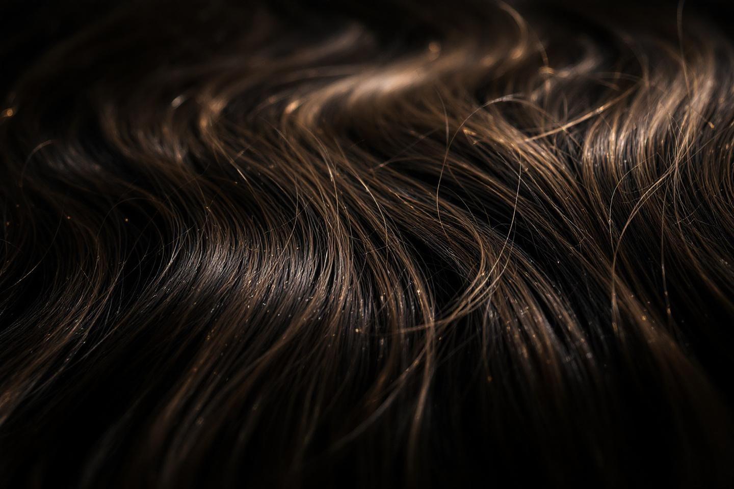 Texture de cheveux bruns sombres avec des reflets dorés