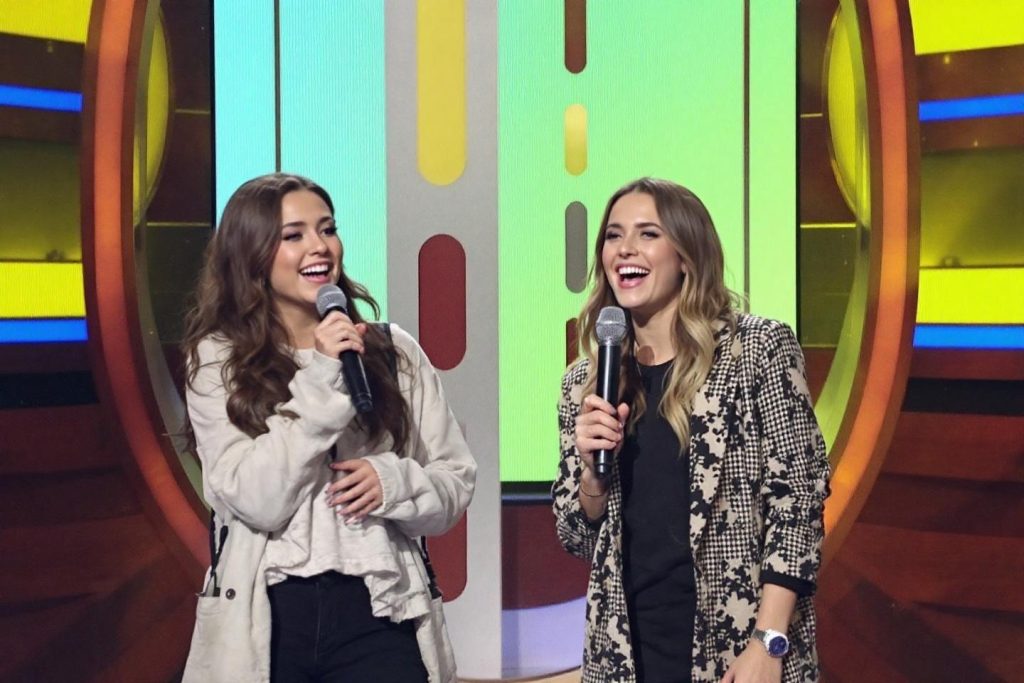 Deux femmes souriantes avec microphones sur fond coloré